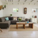Nowoczesna sofa 2-osobowa z funkcją spania w jasnym salonie, szara tapicerka i poduszki